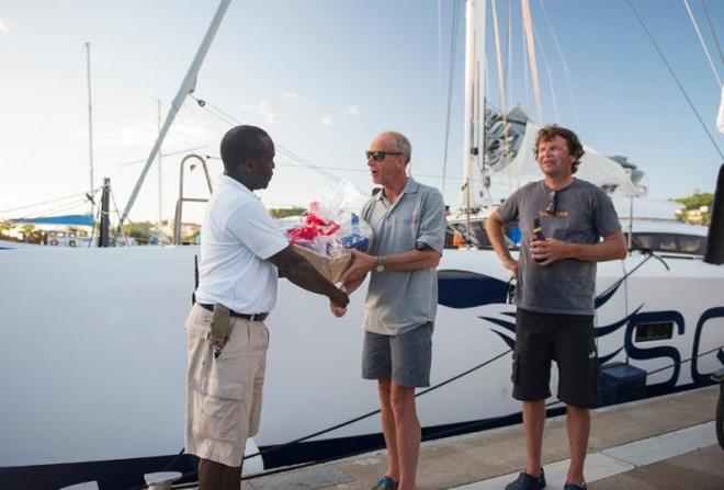 Gerald Bibot and Michel Kleinjans receive a basket of Grenada's finest goods with the compliments of Grenada Tourism  - 2015 RORC Transatlantic Race © Orlando Romain / RORC